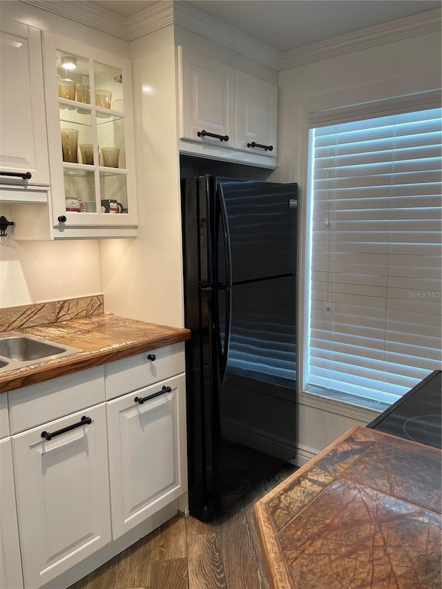 kitchen featuring dark hardwood / wood-style flooring, black fridge, white cabinetry, and crown molding