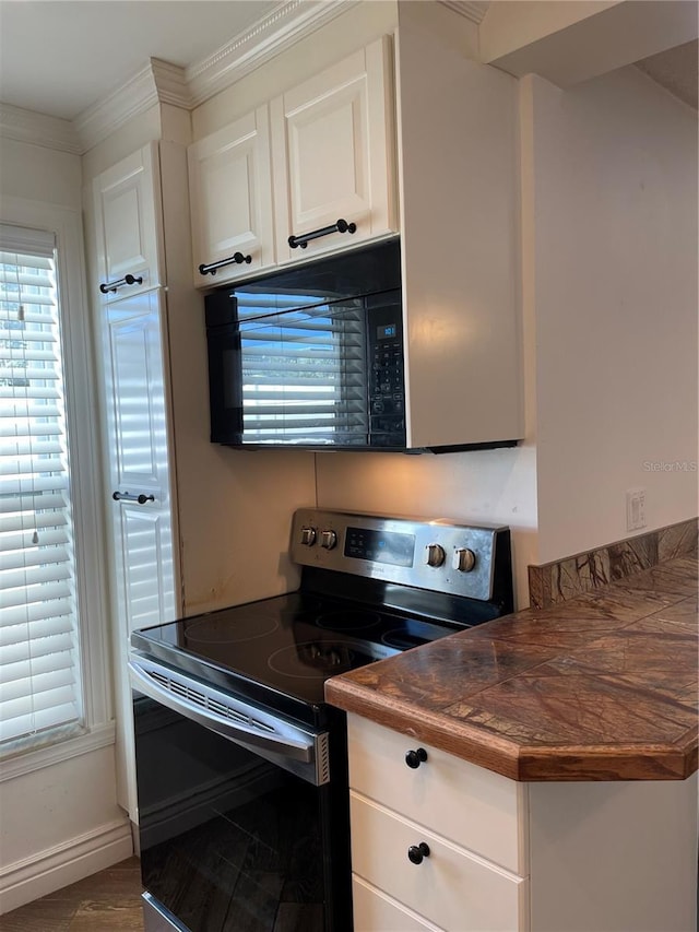 kitchen featuring black appliances, white cabinetry, and ornamental molding