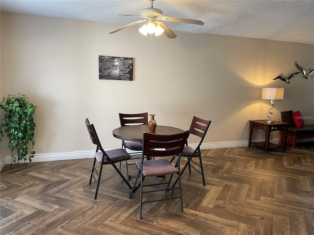 dining area with ceiling fan, dark parquet flooring, and a textured ceiling