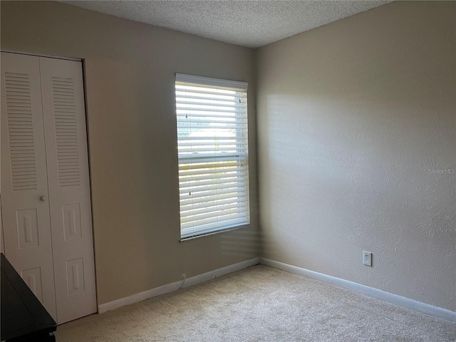 unfurnished bedroom with carpet flooring, a closet, and a textured ceiling