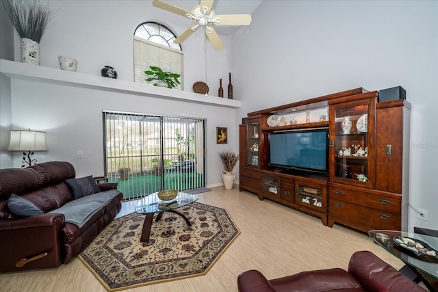 living room featuring ceiling fan, a towering ceiling, and hardwood / wood-style flooring