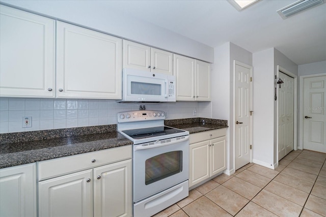 kitchen featuring backsplash, white appliances, light tile patterned floors, dark stone countertops, and white cabinetry