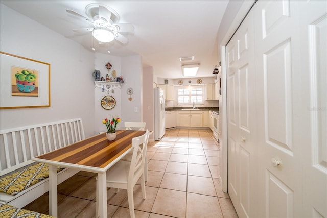 dining space with ceiling fan, light tile patterned floors, and sink