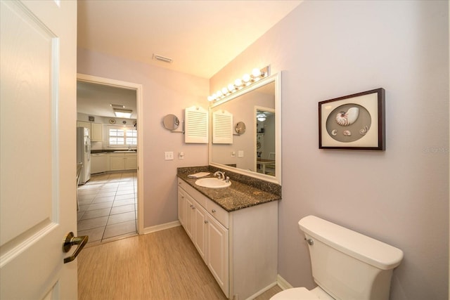 bathroom with vanity, toilet, and wood-type flooring