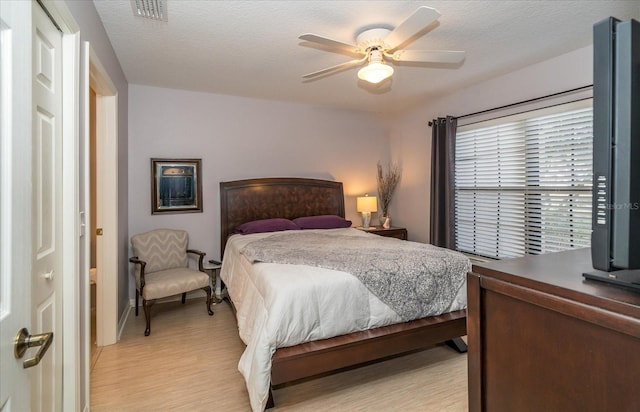 bedroom featuring ceiling fan, light wood-type flooring, and a textured ceiling