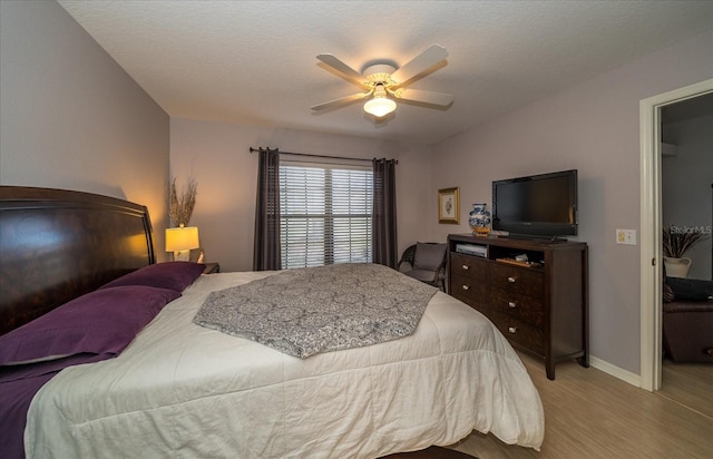 bedroom with ceiling fan, light wood-type flooring, and a textured ceiling