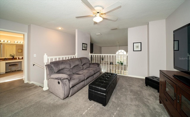 living room featuring carpet flooring, ceiling fan, and a textured ceiling