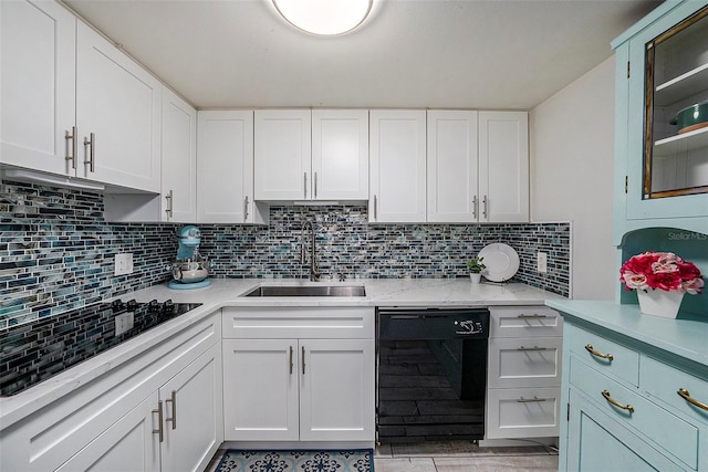 kitchen featuring cooktop, sink, white cabinets, and black dishwasher