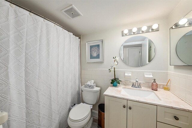 bathroom with vanity, toilet, and tile walls