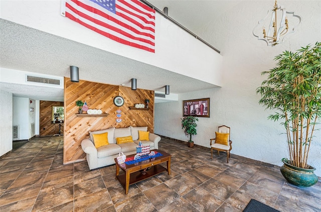 living room featuring a textured ceiling, an inviting chandelier, and wood walls