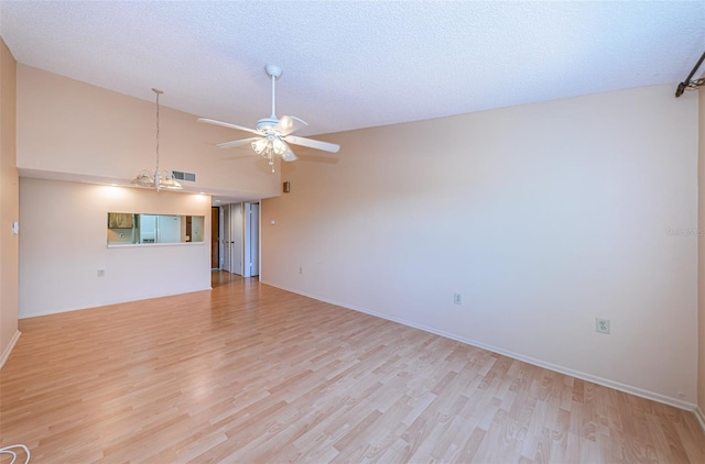 unfurnished living room with a textured ceiling, lofted ceiling, and light wood-type flooring