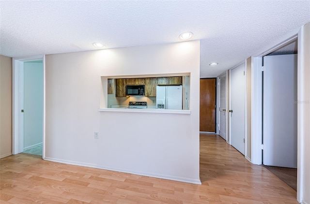 kitchen featuring light hardwood / wood-style floors, white fridge with ice dispenser, a textured ceiling, and range