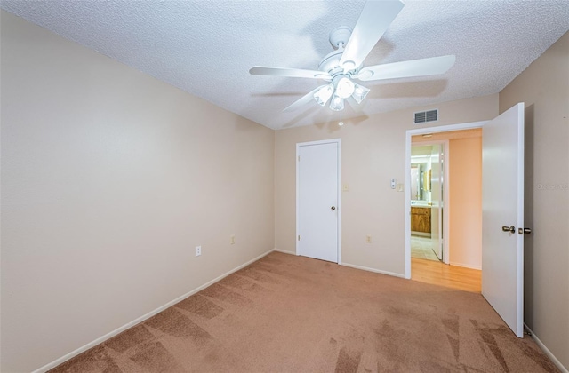 unfurnished bedroom with ceiling fan, light carpet, and a textured ceiling