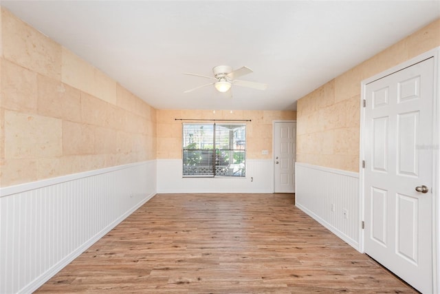 empty room with ceiling fan and light hardwood / wood-style flooring