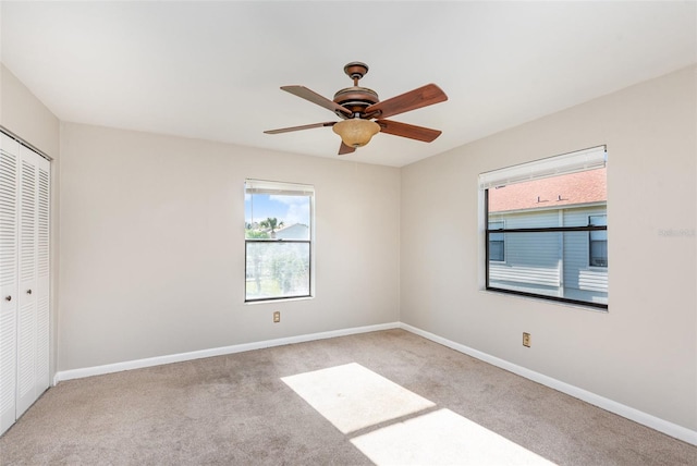 carpeted spare room featuring ceiling fan