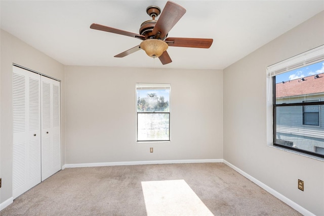 unfurnished bedroom with multiple windows, ceiling fan, a closet, and light carpet