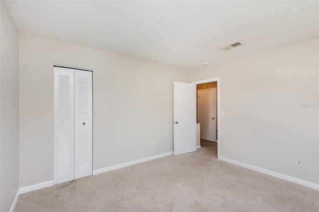 unfurnished bedroom with light carpet and a closet