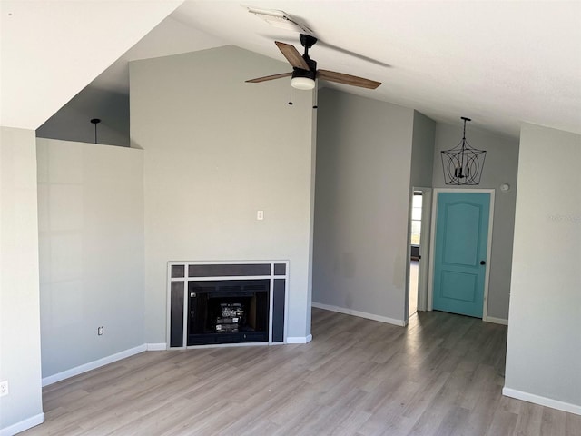 unfurnished living room with ceiling fan with notable chandelier, light hardwood / wood-style floors, and lofted ceiling