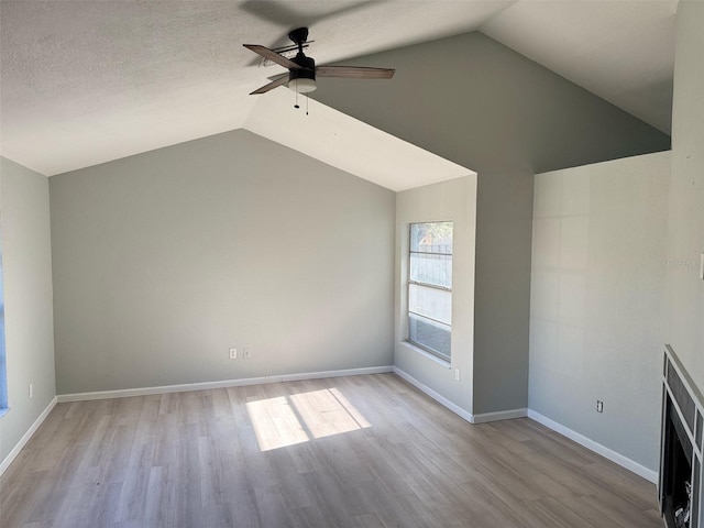 unfurnished living room with ceiling fan, light wood-type flooring, lofted ceiling, and a textured ceiling