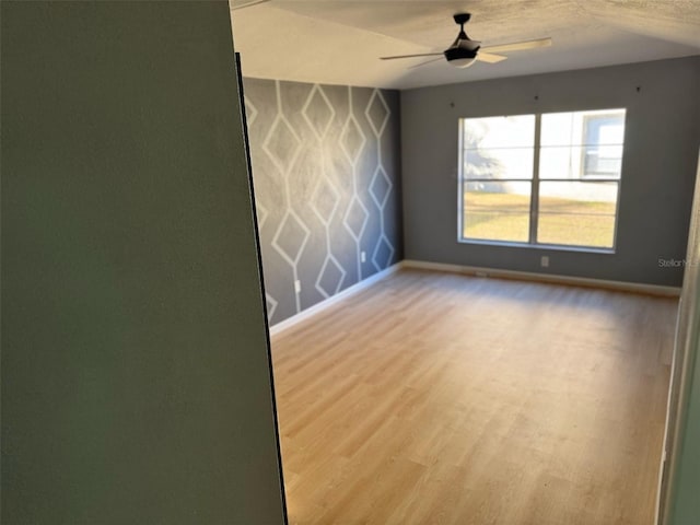 spare room with ceiling fan, a textured ceiling, and light wood-type flooring