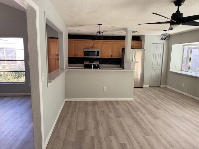 kitchen featuring ceiling fan, light wood-type flooring, tasteful backsplash, kitchen peninsula, and stainless steel appliances