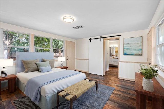 bedroom featuring a barn door and dark hardwood / wood-style floors