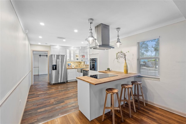 kitchen featuring a breakfast bar, island range hood, black appliances, pendant lighting, and white cabinets