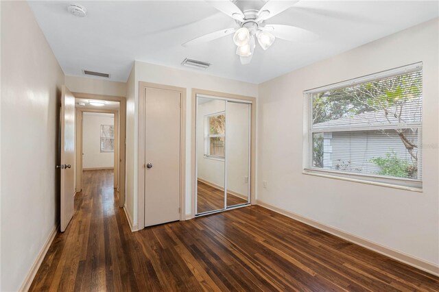 unfurnished bedroom with ceiling fan, dark hardwood / wood-style flooring, and a closet