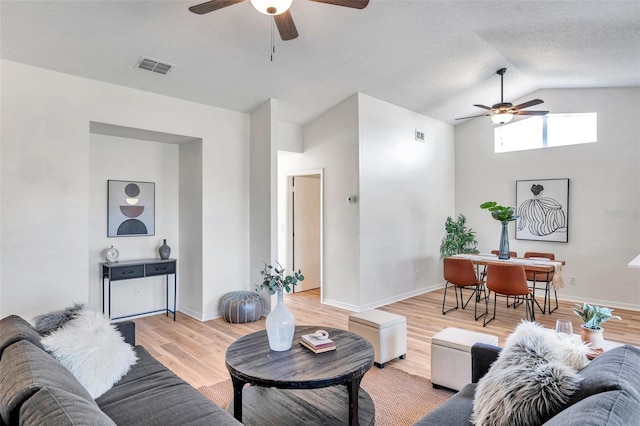 living room with ceiling fan, vaulted ceiling, and light wood-type flooring