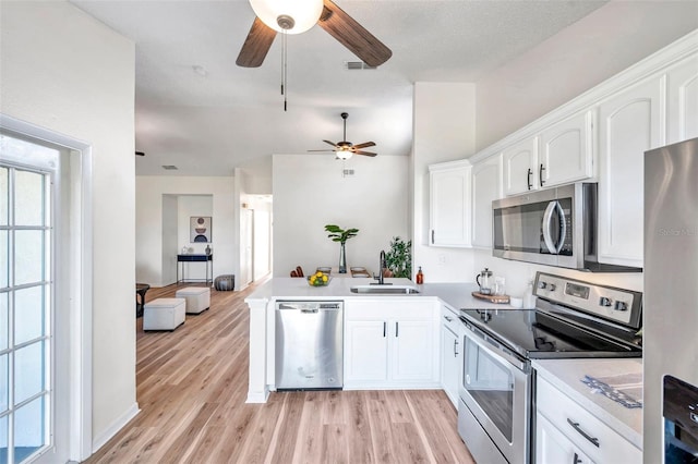 kitchen featuring kitchen peninsula, appliances with stainless steel finishes, sink, light hardwood / wood-style flooring, and white cabinets