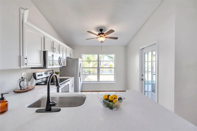 kitchen featuring appliances with stainless steel finishes, vaulted ceiling, sink, white cabinets, and plenty of natural light