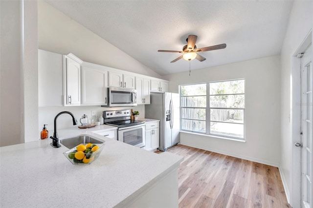 kitchen with white cabinetry, sink, stainless steel appliances, light hardwood / wood-style flooring, and vaulted ceiling