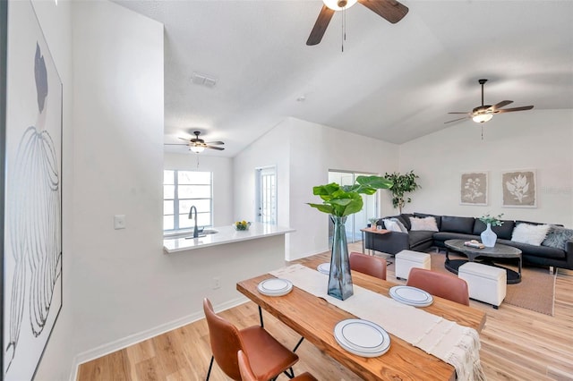 dining room with sink, light hardwood / wood-style flooring, and vaulted ceiling