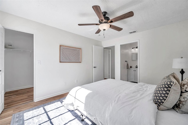 bedroom with ensuite bathroom, ceiling fan, light hardwood / wood-style flooring, a spacious closet, and a closet