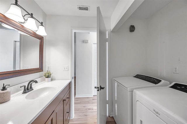 bathroom with wood-type flooring, vanity, and separate washer and dryer