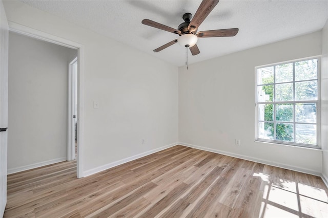 spare room featuring a textured ceiling, light wood-type flooring, and ceiling fan