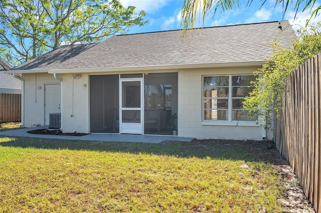 back of house featuring a lawn, a sunroom, and central AC unit