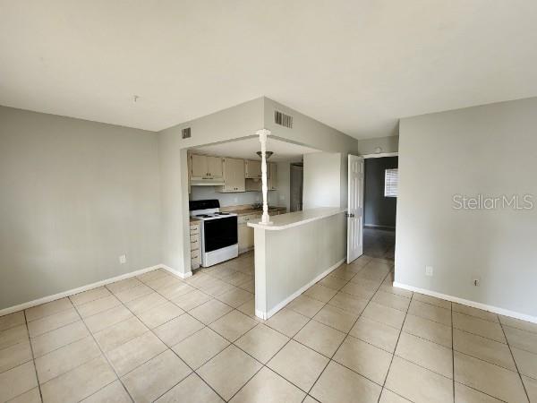 kitchen with electric stove, kitchen peninsula, and light tile patterned flooring