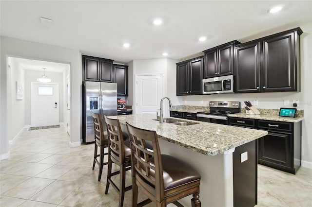 kitchen featuring appliances with stainless steel finishes, a center island with sink, a kitchen breakfast bar, and sink