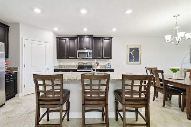 kitchen featuring a kitchen bar, sink, stainless steel appliances, and an island with sink