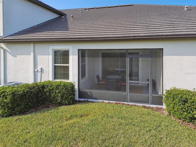 rear view of property featuring a sunroom and a yard