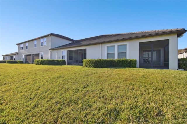 10374 Echo Dock Loop, San Antonio, FL 33576 - rear view of house featuring a sunroom, stucco siding, and a lawn