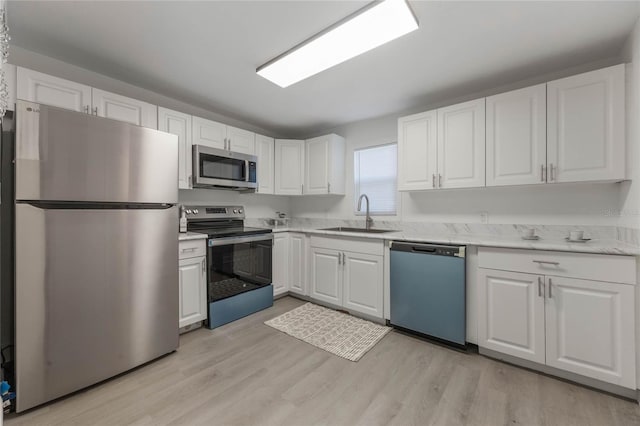 kitchen with stainless steel appliances, light hardwood / wood-style floors, white cabinets, and sink