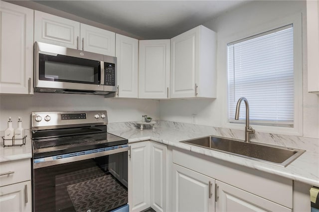 kitchen with white cabinets, light stone countertops, sink, and stainless steel appliances