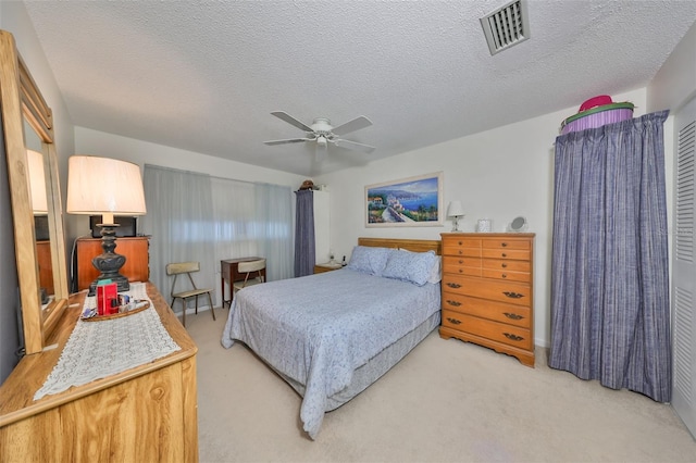 carpeted bedroom with ceiling fan and a textured ceiling