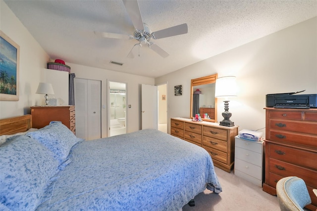 carpeted bedroom featuring ensuite bathroom, a closet, ceiling fan, and a textured ceiling