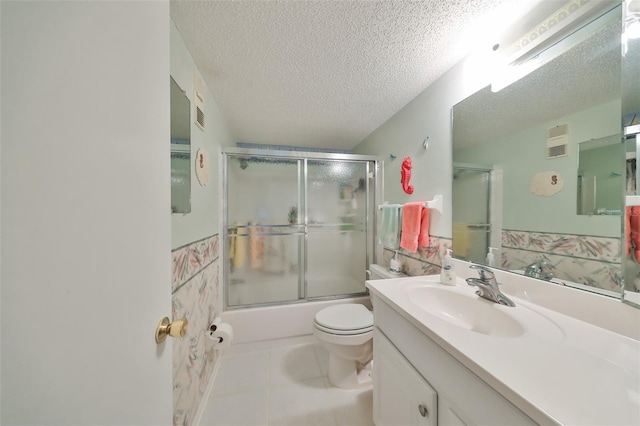 full bathroom featuring tile patterned floors, a textured ceiling, toilet, shower / bath combination with glass door, and vanity