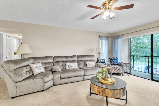 carpeted living room featuring ceiling fan and a textured ceiling