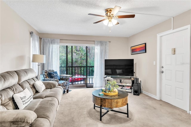 living room with a textured ceiling, light colored carpet, and ceiling fan