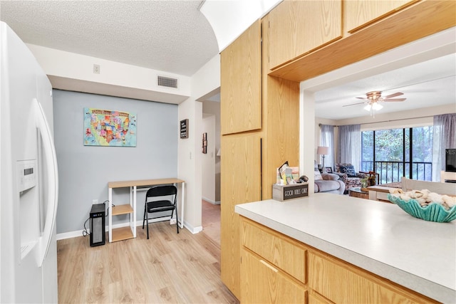 kitchen with ceiling fan, light brown cabinets, light hardwood / wood-style flooring, white refrigerator with ice dispenser, and a textured ceiling